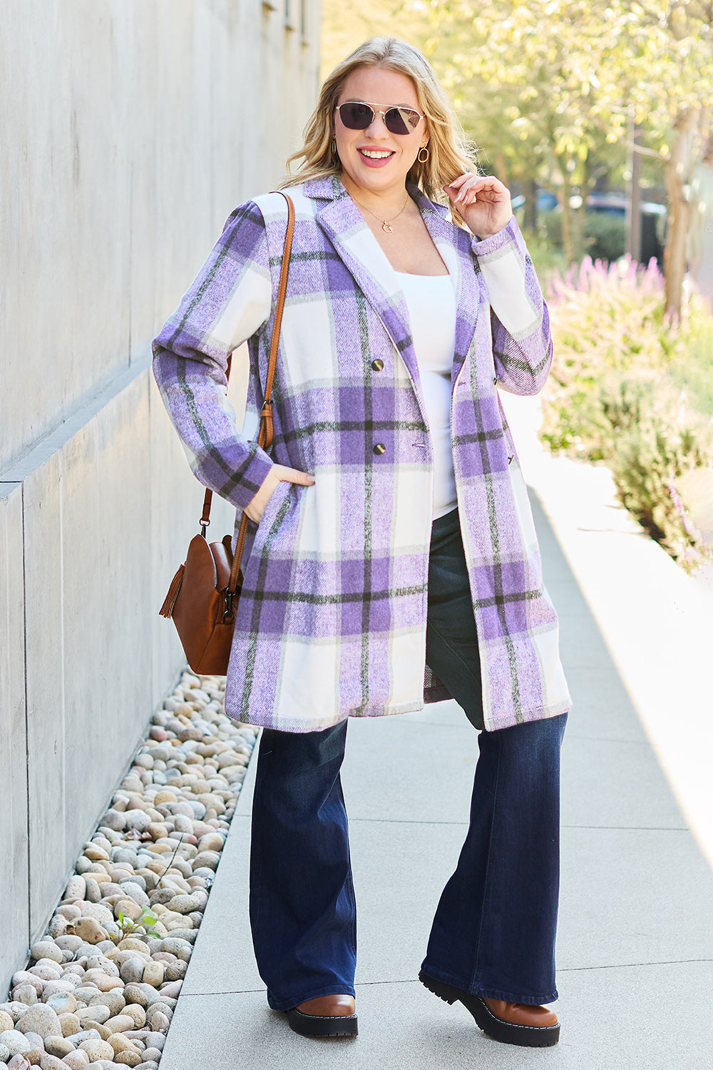 Woman wearing full-size plaid button-up lapel collar coat with pockets, paired with wide-legged jeans and sunglasses outdoors.