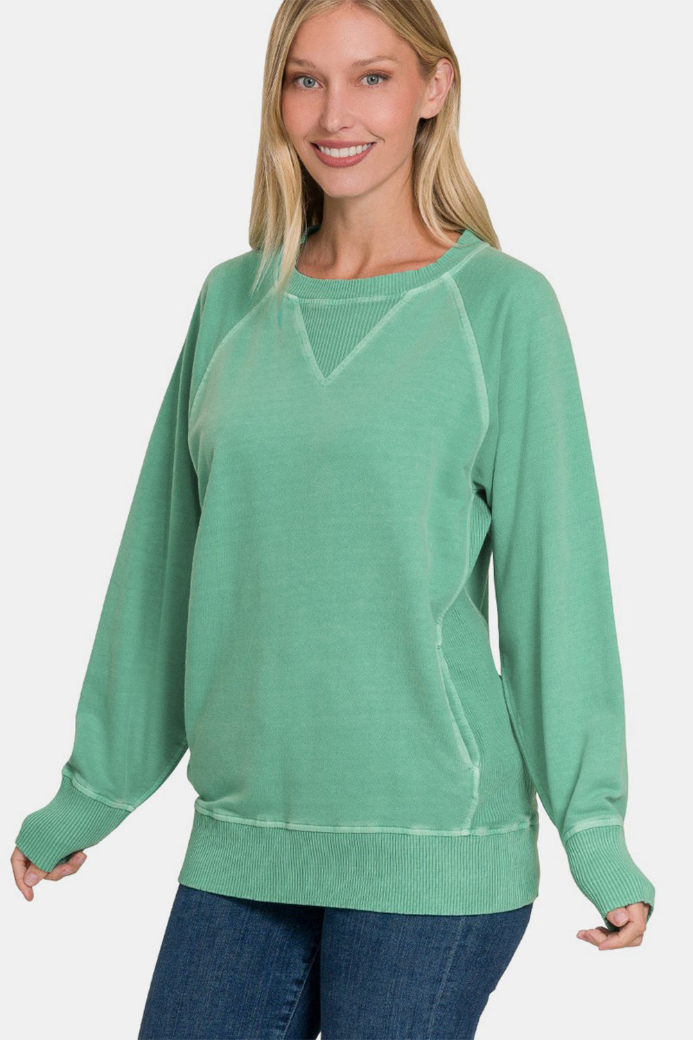 Woman wearing a green pocketed round neck long sleeve sweatshirt made of 100% cotton.