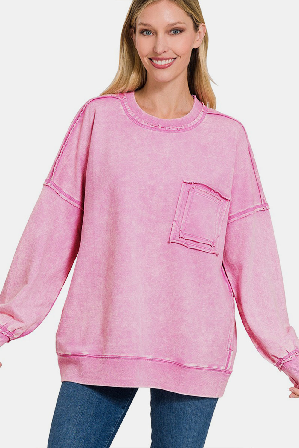 Woman wearing pink round neck dropped shoulder sweatshirt with exposed seams and front pocket, moderate stretch, 100% cotton.