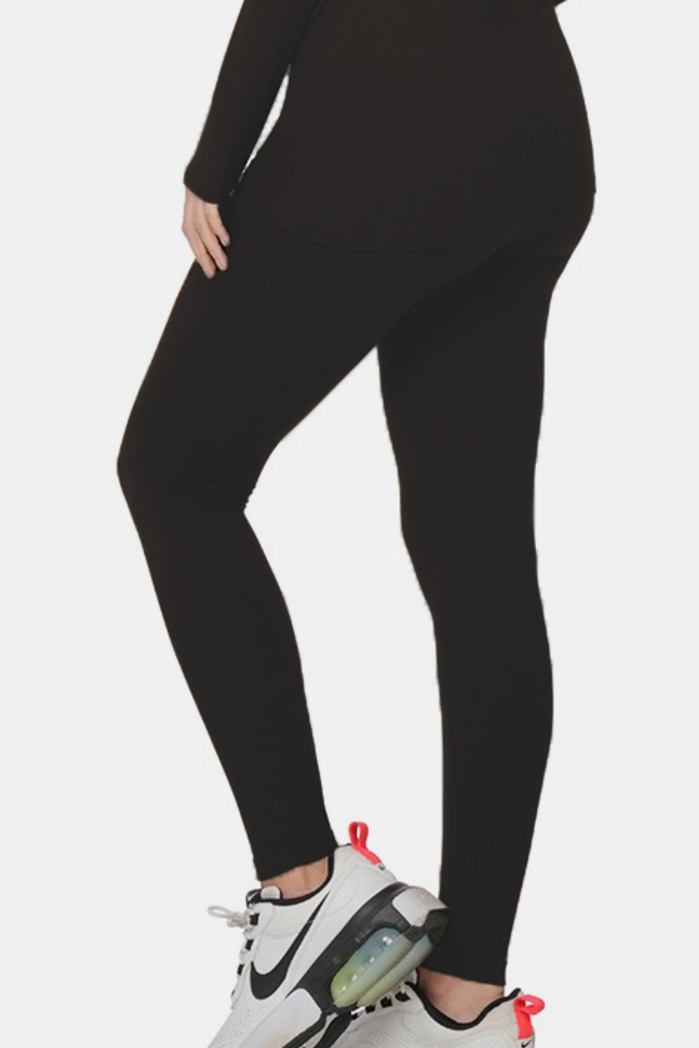 Woman wearing black turtleneck top and leggings lounge set with white sneakers, showcasing chic, comfortable style.