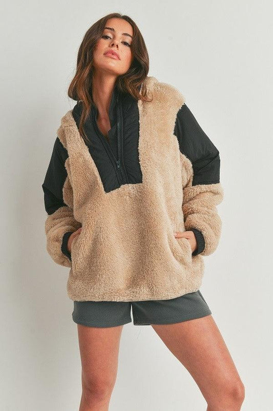 Woman wearing two-toned taupe and black cozy hooded sweater, soft fabric, casual style, 100% polyester.