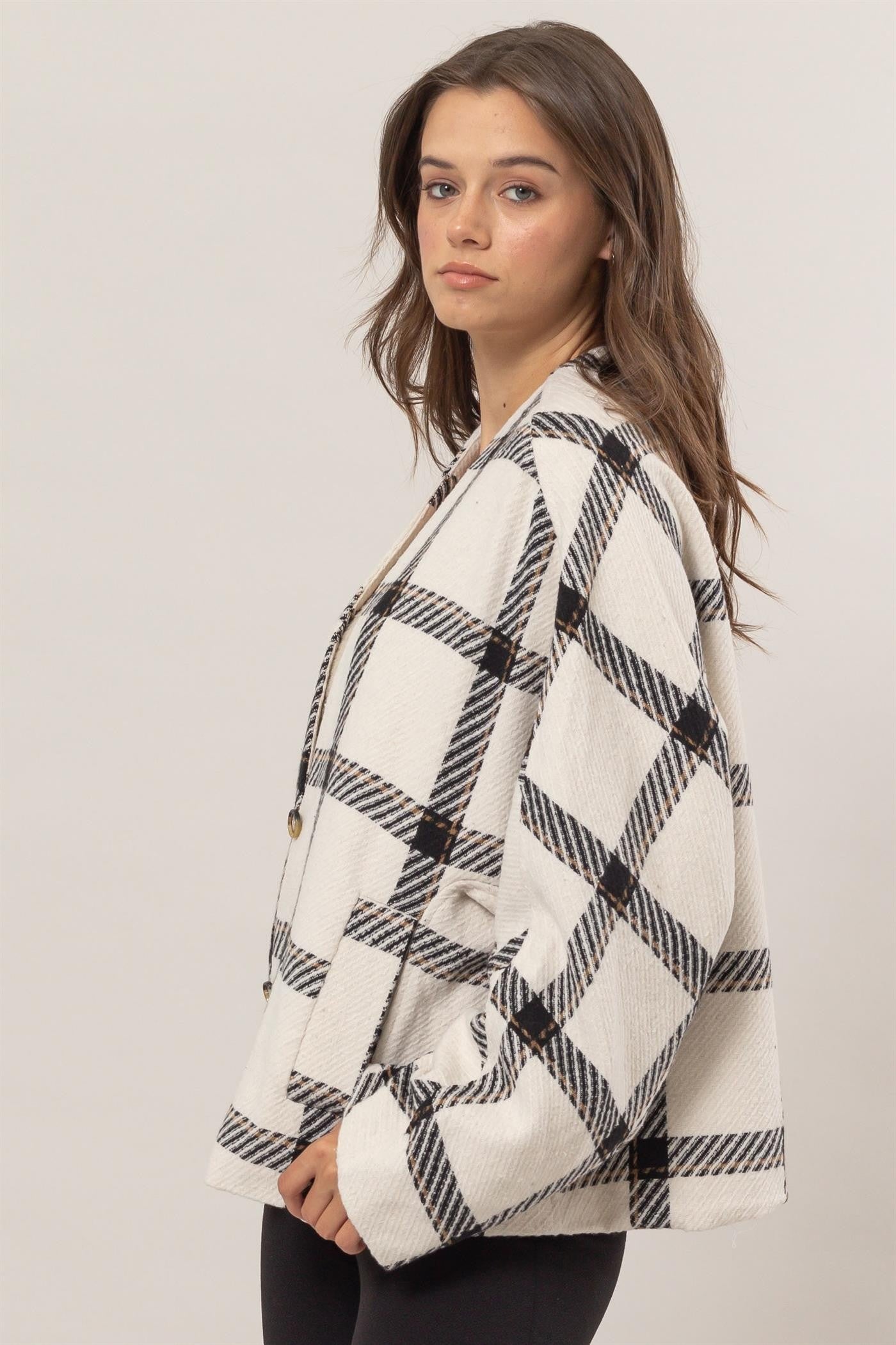 Woman wearing cream plaid long sleeve jacket with side slit pockets, buttoned front, made of 100% polyester.