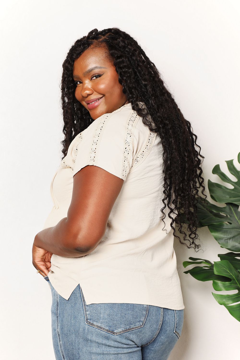 Woman wearing crochet buttoned short sleeves top, side view.