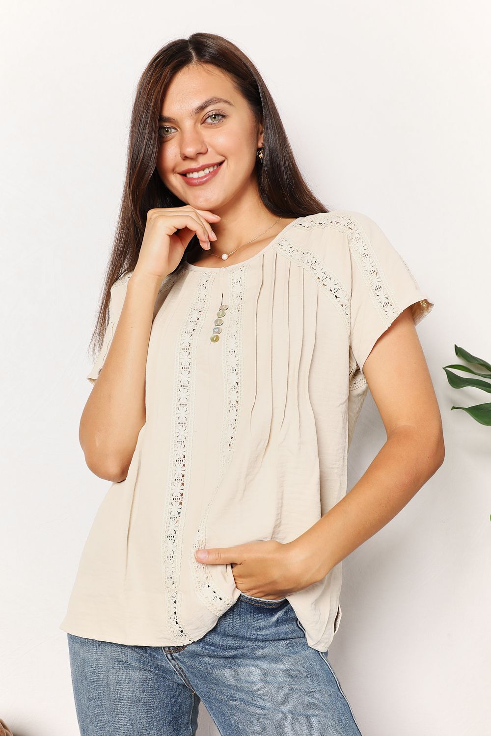 Woman wearing a chic crochet buttoned short sleeve top with jeans, featuring a round neckline and boho vibe.