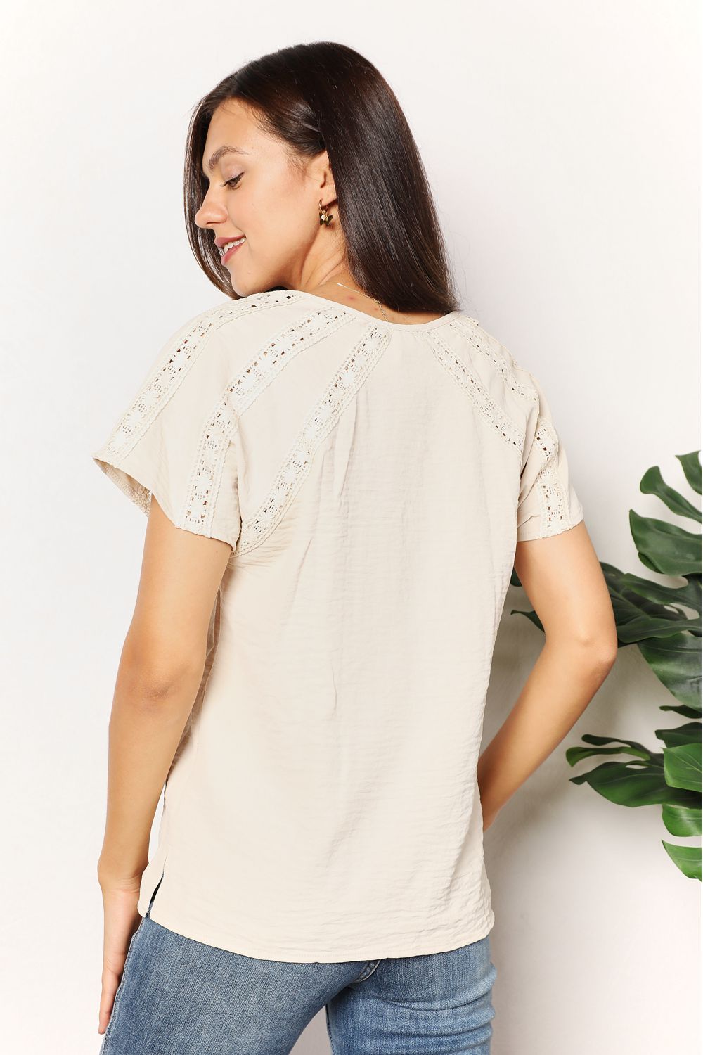 Woman wearing Double Take Crochet Buttoned Short Sleeves Top in neutral color with stylish back details.