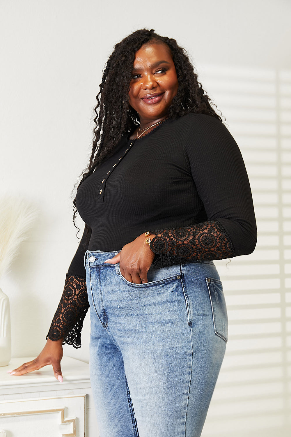 Woman modeling black crochet lace hem sleeve button top with jeans, showcasing feminine and versatile fashion style.