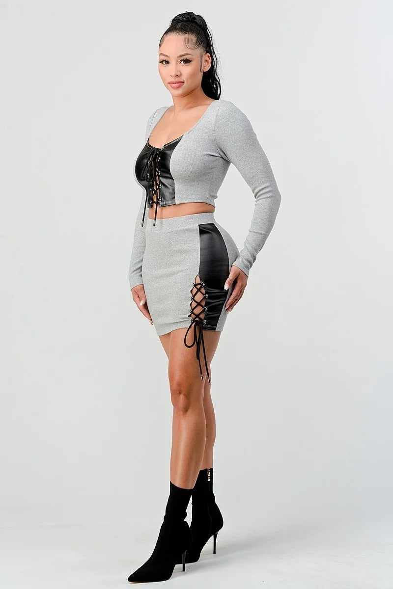 Grey cropped long sleeve shirt set with faux leather, crisscross lacing details, paired with a matching mini skirt.