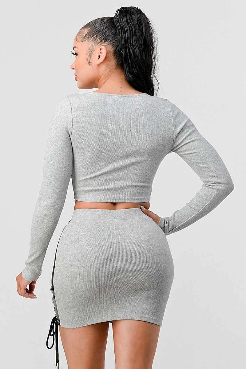 Grey cropped long sleeve shirt and faux leather mini skirt set with crisscross lacing, viewed from the back.