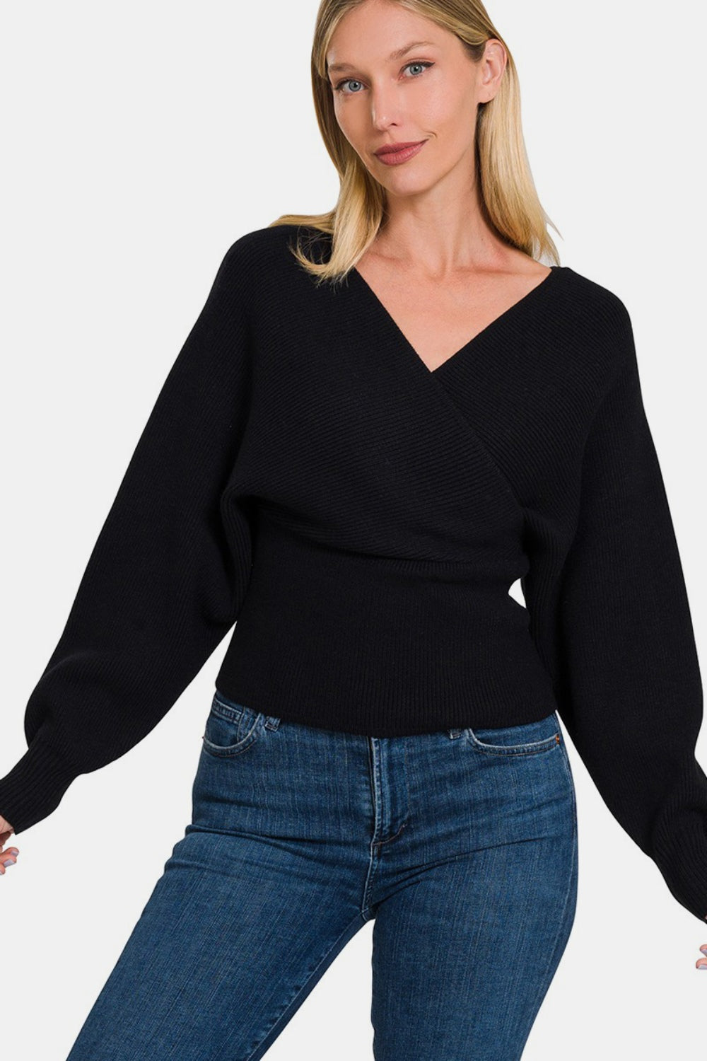 Woman wearing a chic black cross wrap rib long sleeve sweater paired with blue jeans.