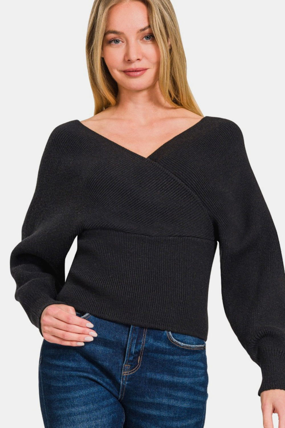 Woman wearing a chic black cross wrap rib long sleeve sweater with jeans, offering a stylish and versatile look for day to night.