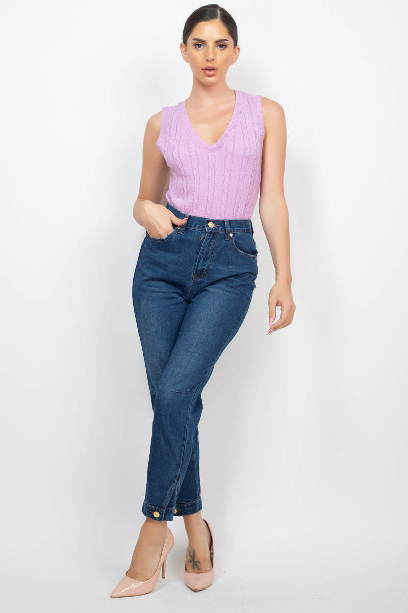 Woman wearing dark denim mom jeans with high-rise waist, princess seams, cuffed-button hem, paired with a pink sleeveless top.