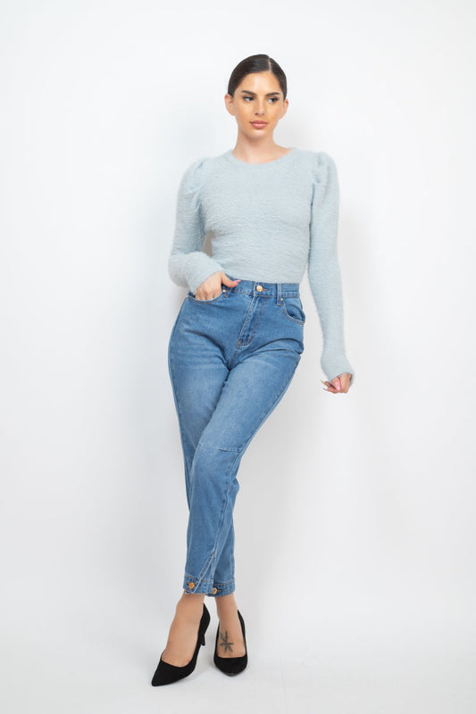 Woman wearing medium denim cuffed-button mom jeans with high-rise waist and Capri-length hem, paired with a light blue long-sleeve top.