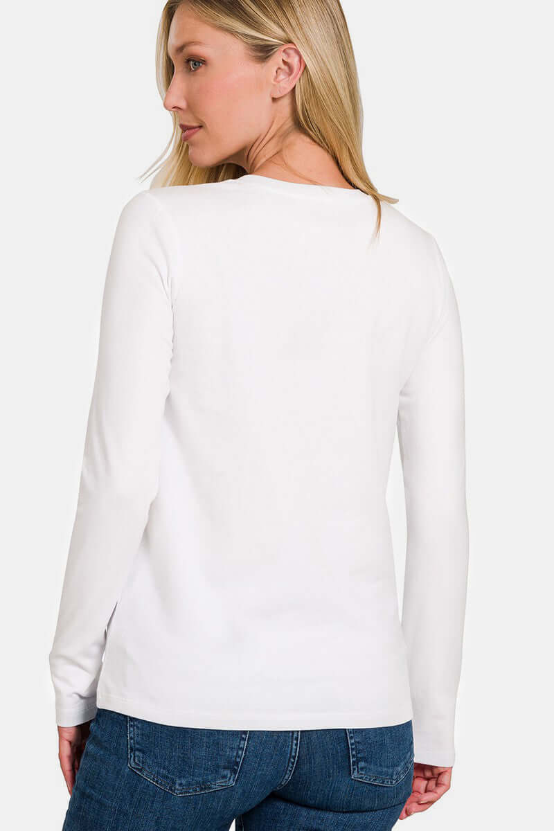 Woman wearing white round neck long sleeve t-shirt, back view, paired with jeans.