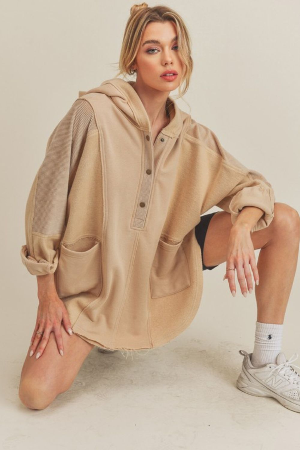 Beige oat slit half snap oversize hoodie with pockets, ribbed and raw hem design, worn by model in casual athletic pose.