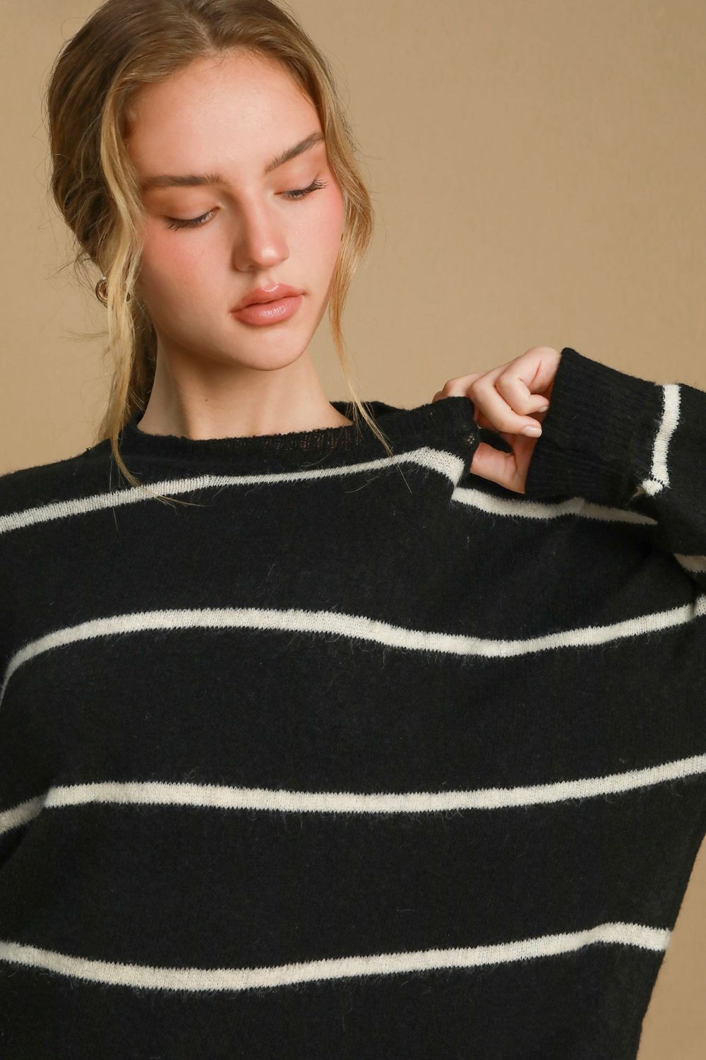 Woman wearing a wool blend striped round neck sweater with ribbed edges, featuring a simple, elegant design.