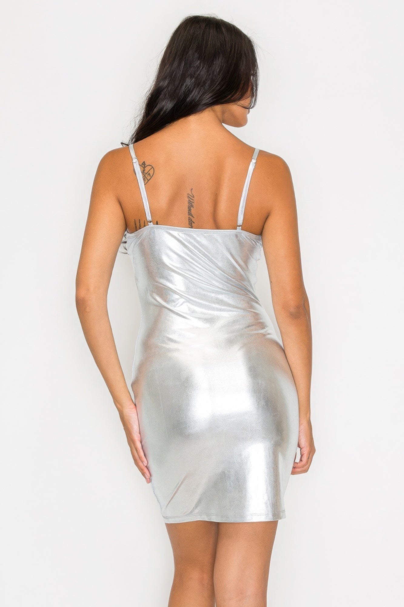 Woman wearing silver scoop neck foil mini dress with adjustable straps, showcasing a shimmering, bodycon silhouette.