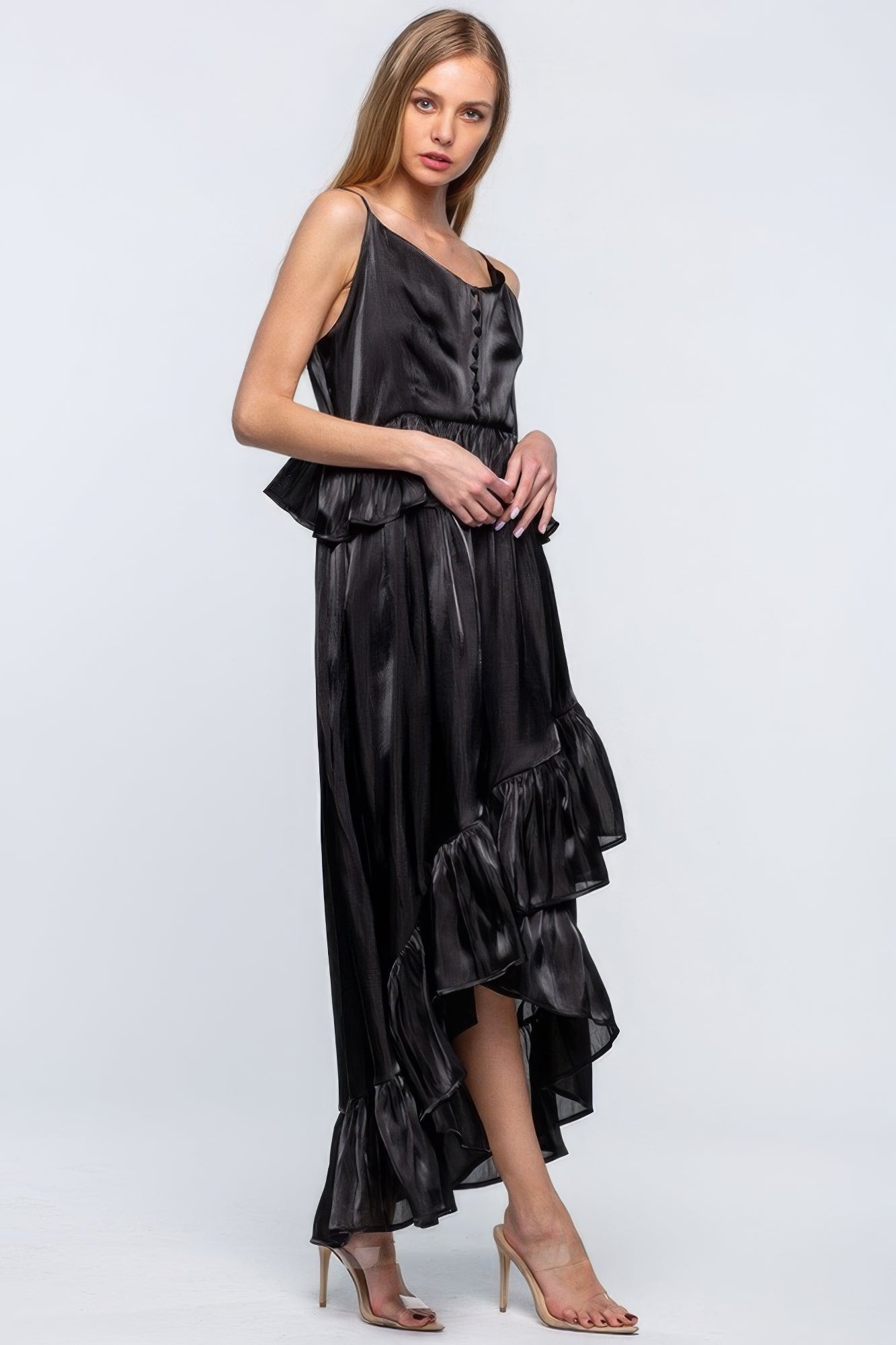 Woman wearing a sleeveless black shimmering dress with ruffles and asymmetric hemline, perfect for elegant occasions.