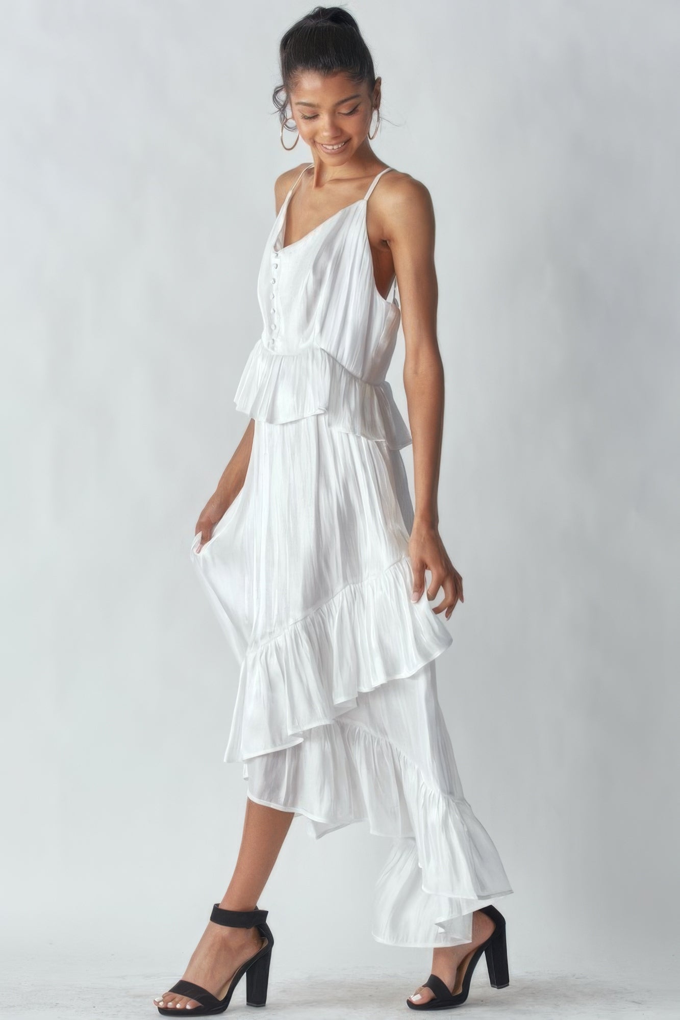 Elegant sleeveless white asymmetric ruffle dress with adjustable straps and eye-catching hemline on a woman, perfect for special occasions.