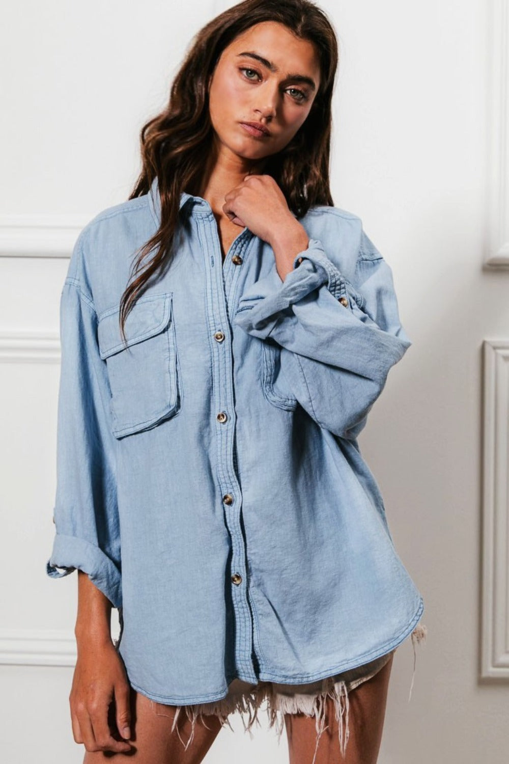 Denim button-down shirt with stitch details and chest pockets, styled casually.