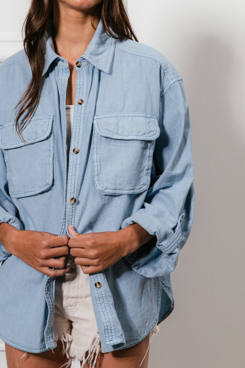 Denim button-down shirt with stitch detail and chest pockets, styled with casual shorts.