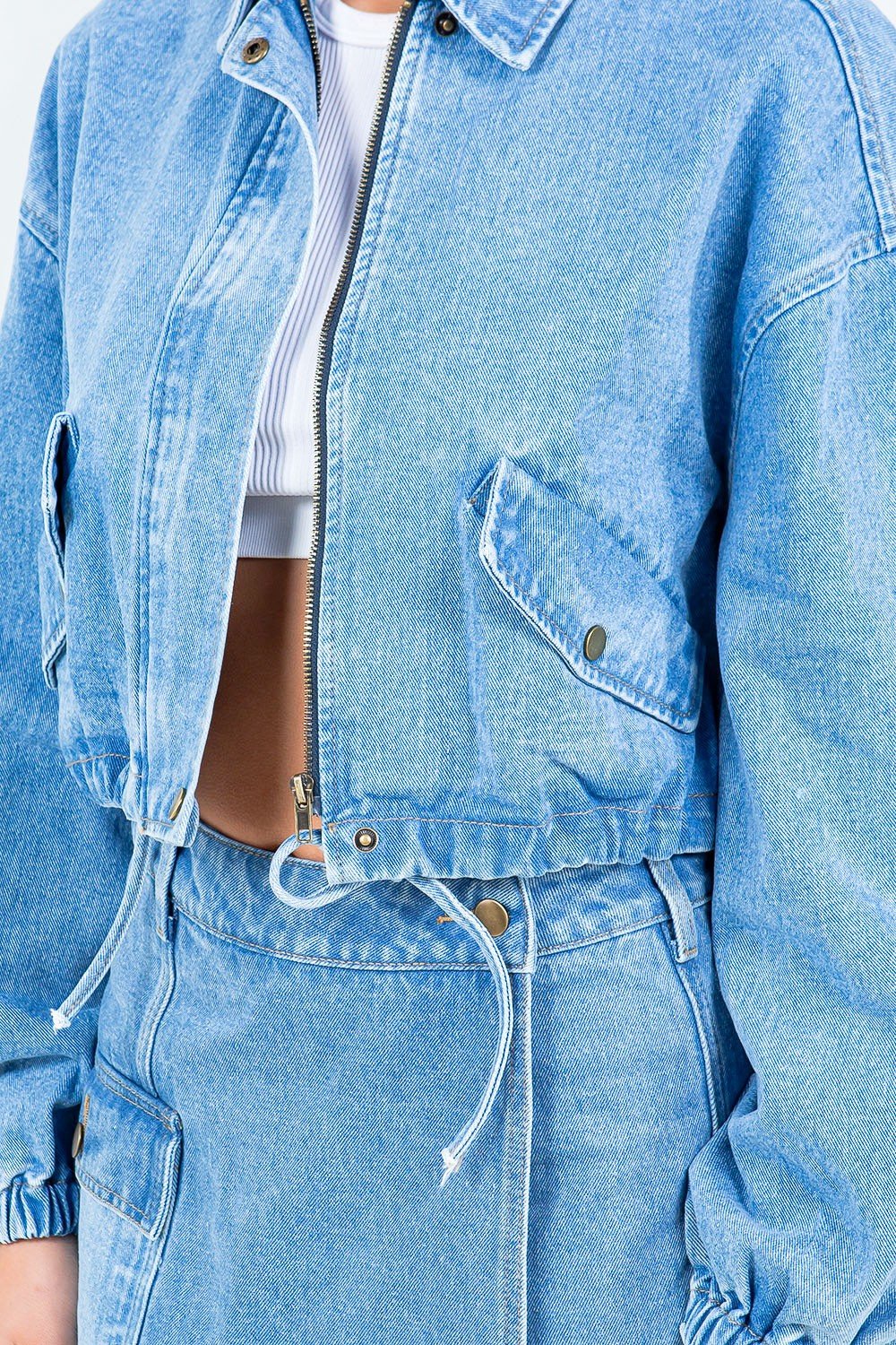 Crop denim jacket with drawstring waist and zipper closure, offering a stylish and comfortable fit with elastic cuffs and hem.