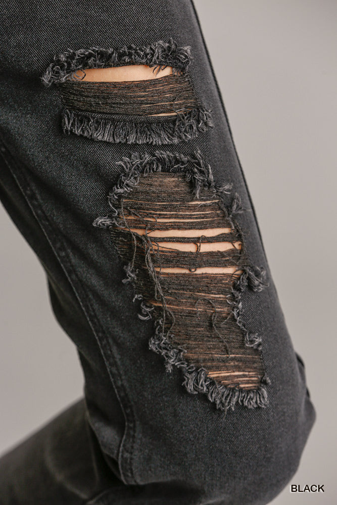 Close-up of distressed black denim jeans with raw hem and frayed details, showcasing the straight cut and non-stretch material.