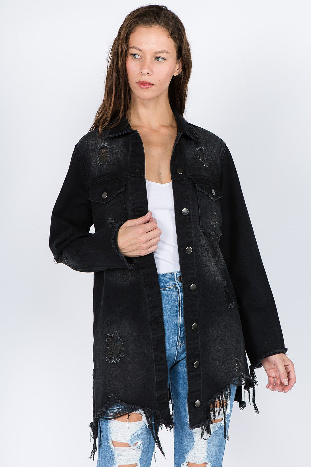 Woman wearing distressed frayed hem denim jacket with edgy raw details and button-front closure, styled with ripped jeans.