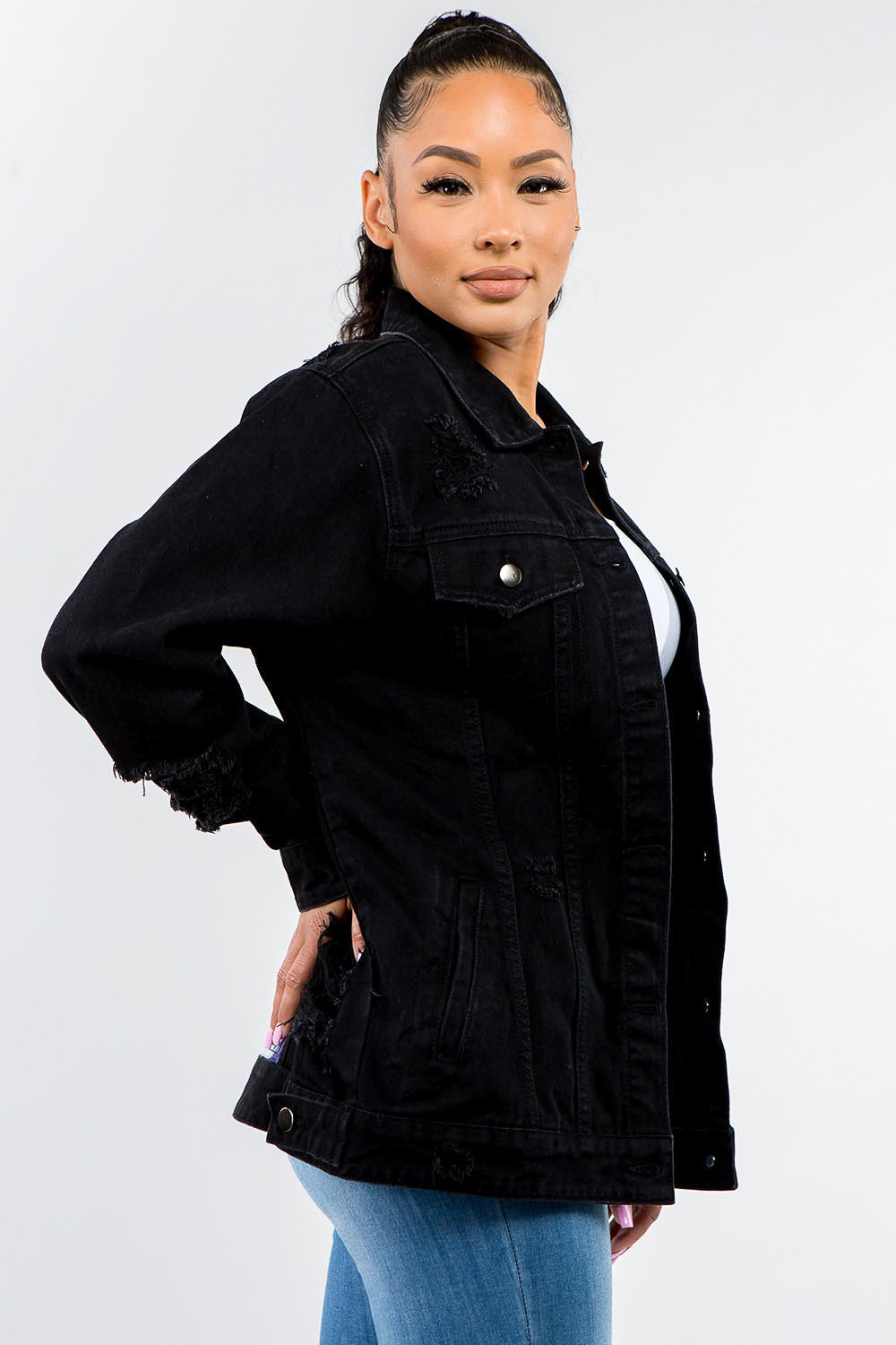 Woman wearing full-size button-up distressed black denim jacket styled with jeans for a casual edgy look.