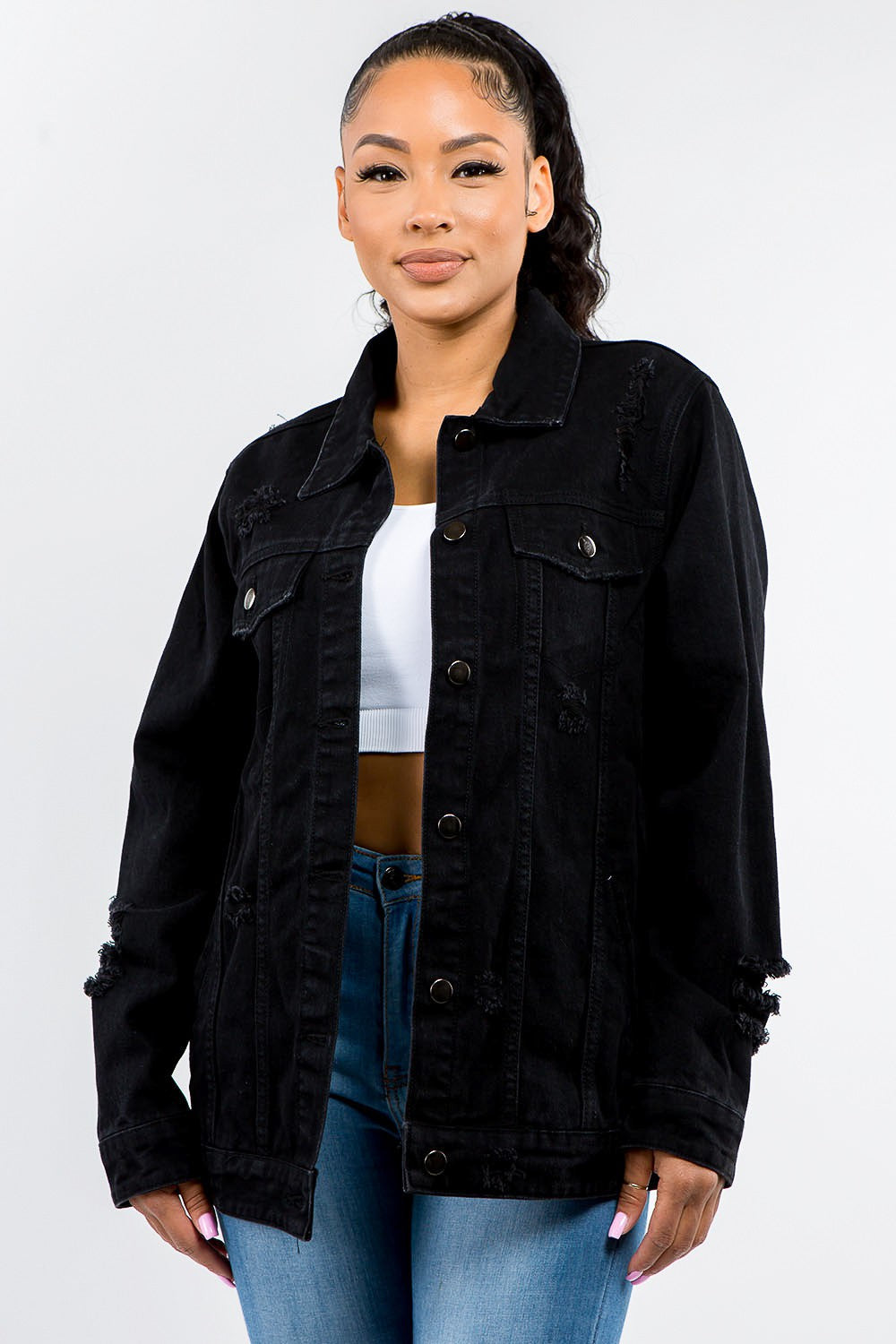 Woman wearing a full-size black distressed denim jacket, showcasing its vintage-inspired edgy style and button-up design.