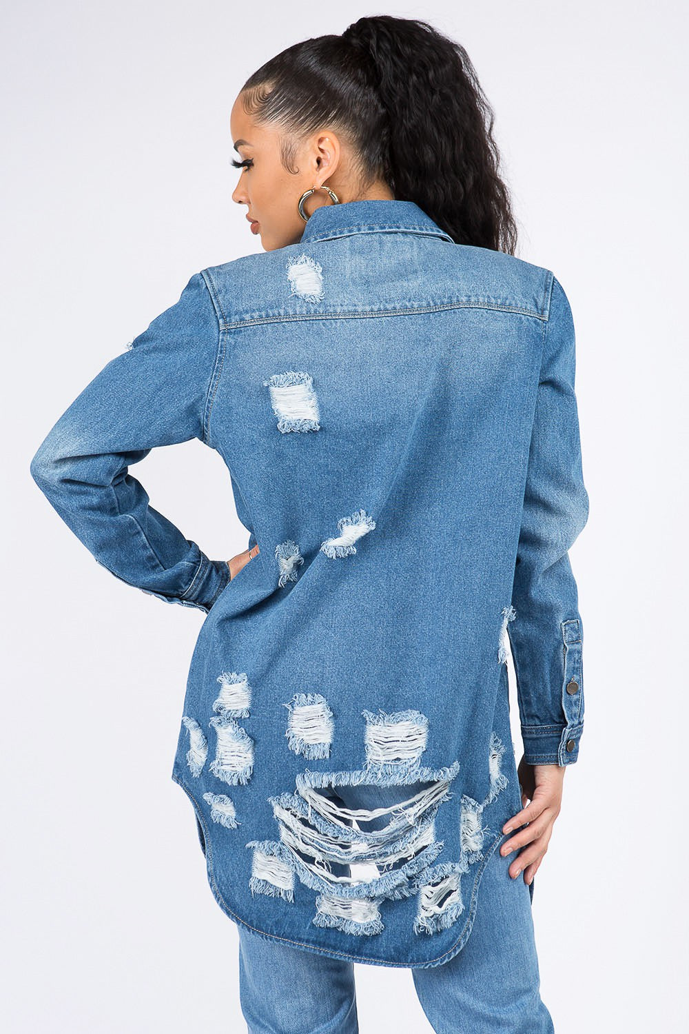 Woman wearing distressed button-down denim shirt jacket with raw hem and edgy style, perfect for casual and chic looks.