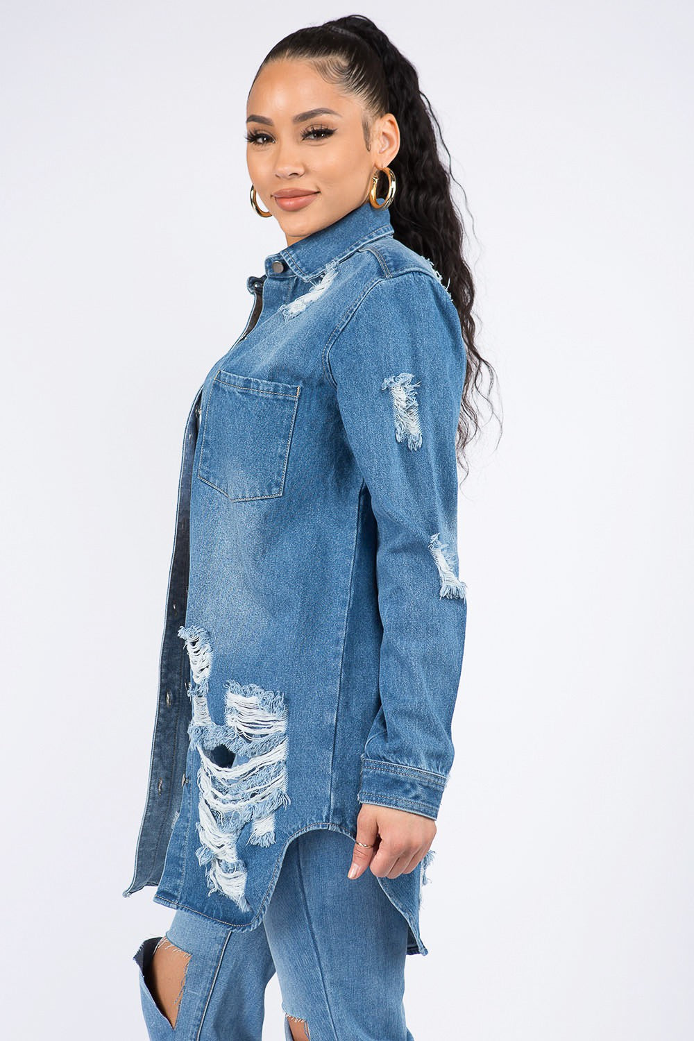 Woman wearing distressed button-down denim shirt jacket with raw hem, showcasing trendy casual style and comfort.