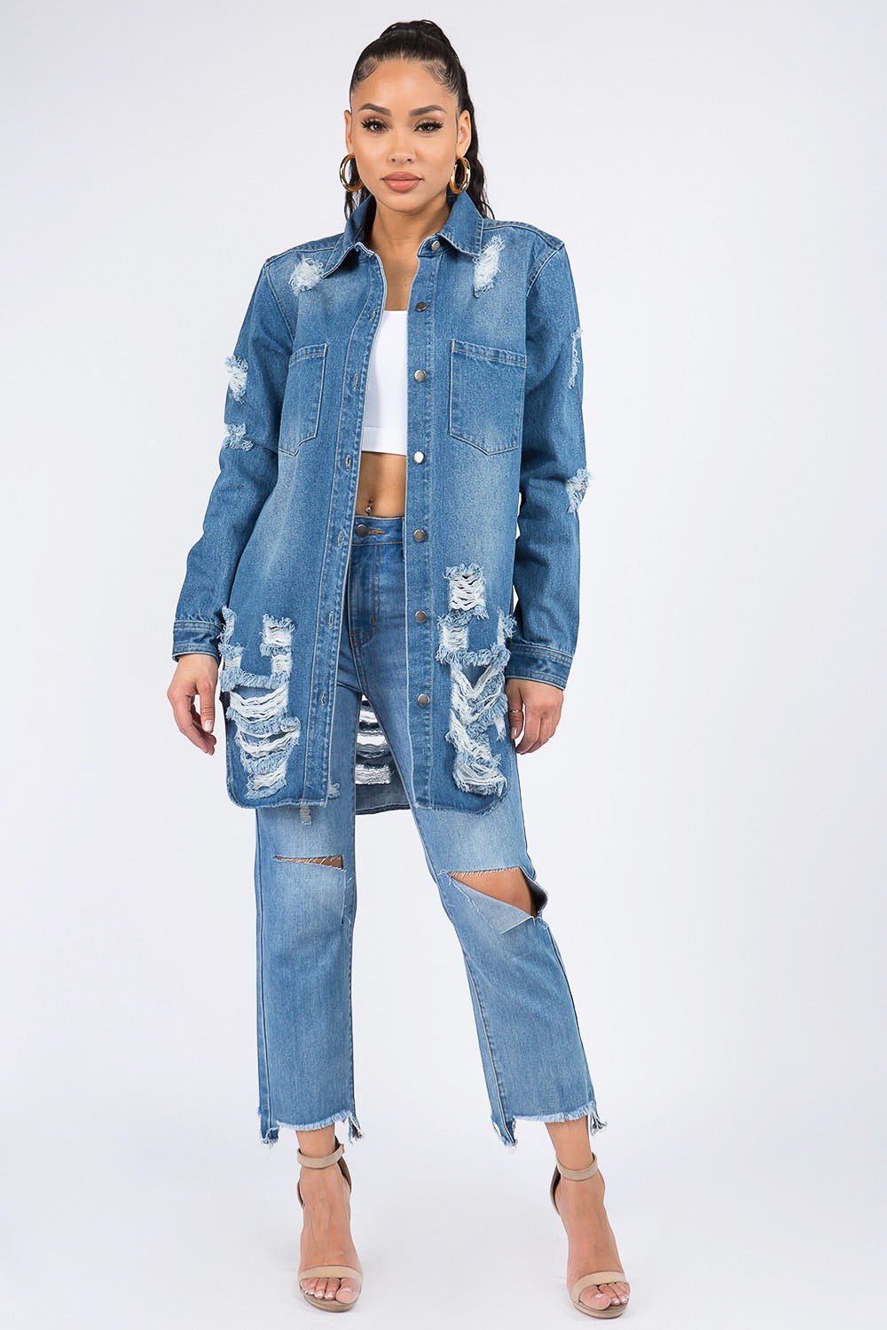 Distressed button-down denim shirt jacket with raw hem, trendy and versatile, styled with matching jeans for a chic look.