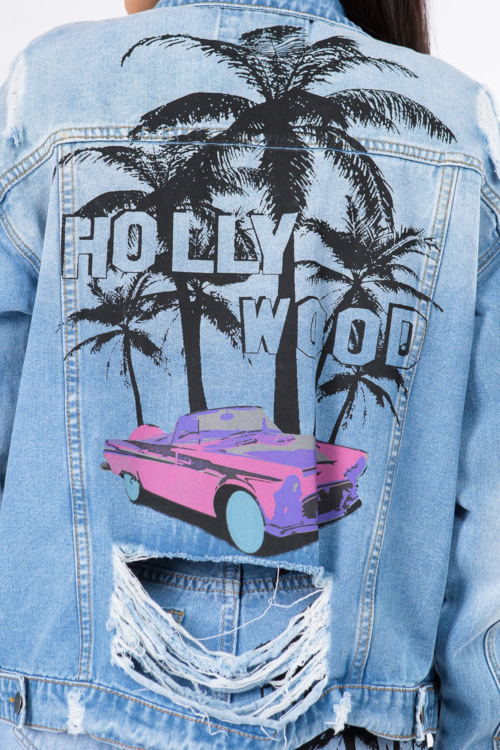 Graphic distressed denim jacket with Hollywood palm tree and car design on back, featuring vintage-inspired torn detailing.