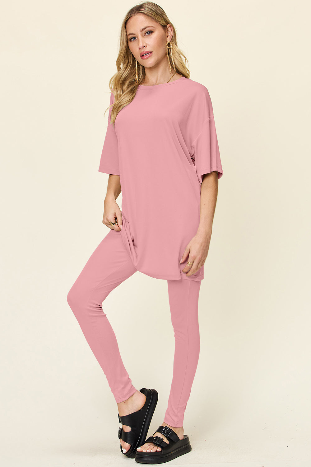 Woman wearing Double Take full size dropped shoulder t-shirt and leggings set in pink, made of polyester and spandex.