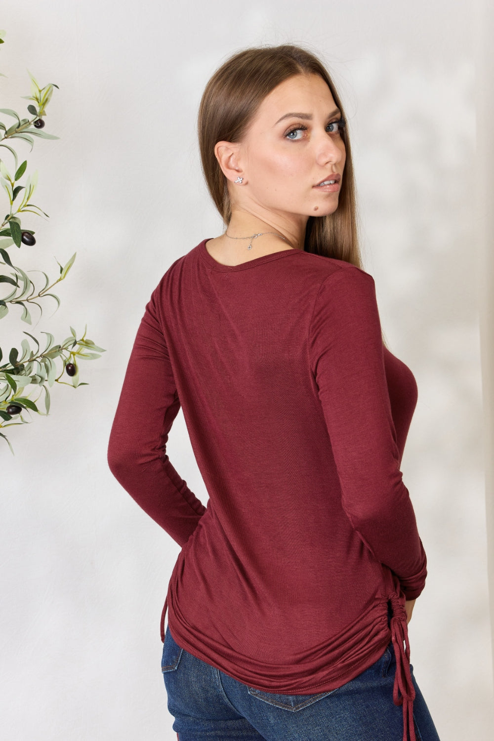 Woman wearing a burgundy drawstring round neck long sleeve top, made of stretchy rayon and spandex, with a stylish casual look.