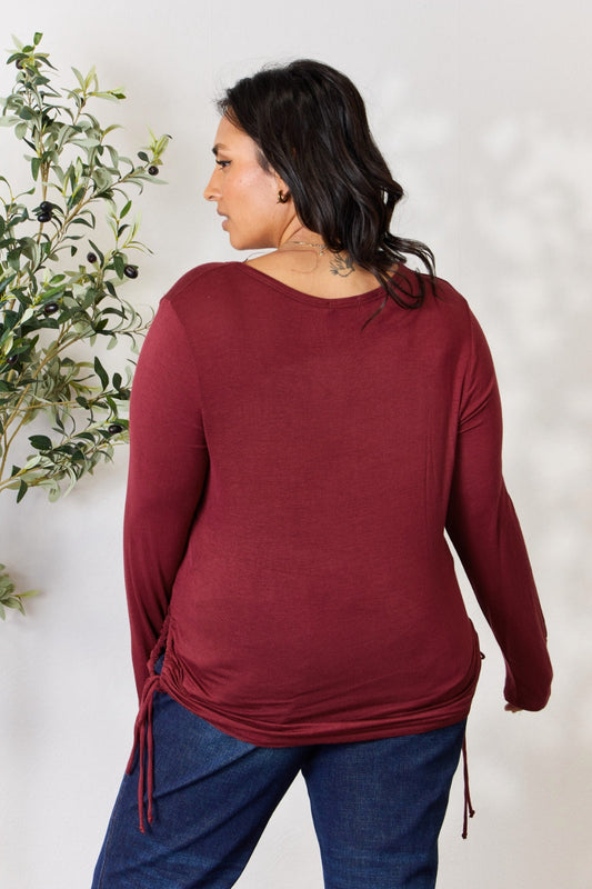 Woman wearing a burgundy drawstring round neck long sleeve top made of rayon and spandex, showcasing its stretch and style.