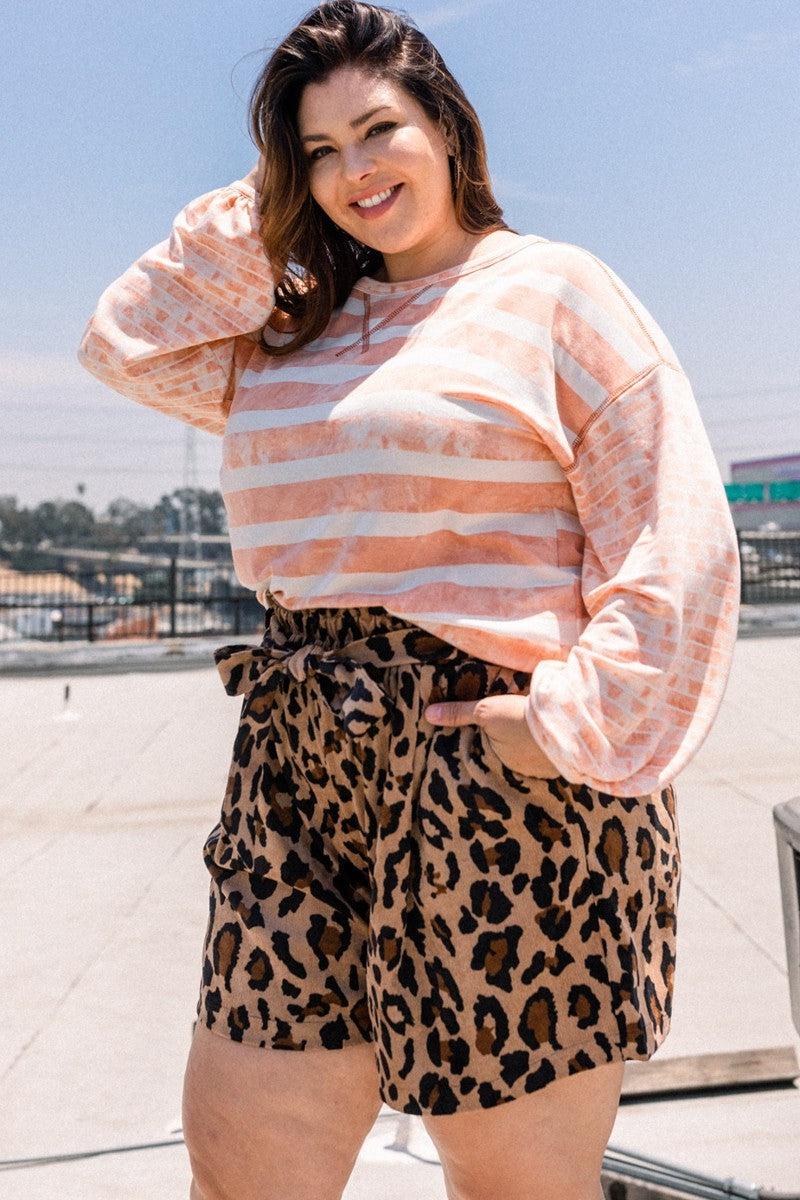 Woman wearing a dusty pink stripe printed French terry top with round neckline and contrast sleeves, paired with leopard print shorts.