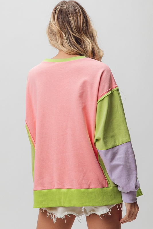 Cool washed color block sweatshirt with slit and exposed seams, featuring vibrant pink, green, and purple hues.