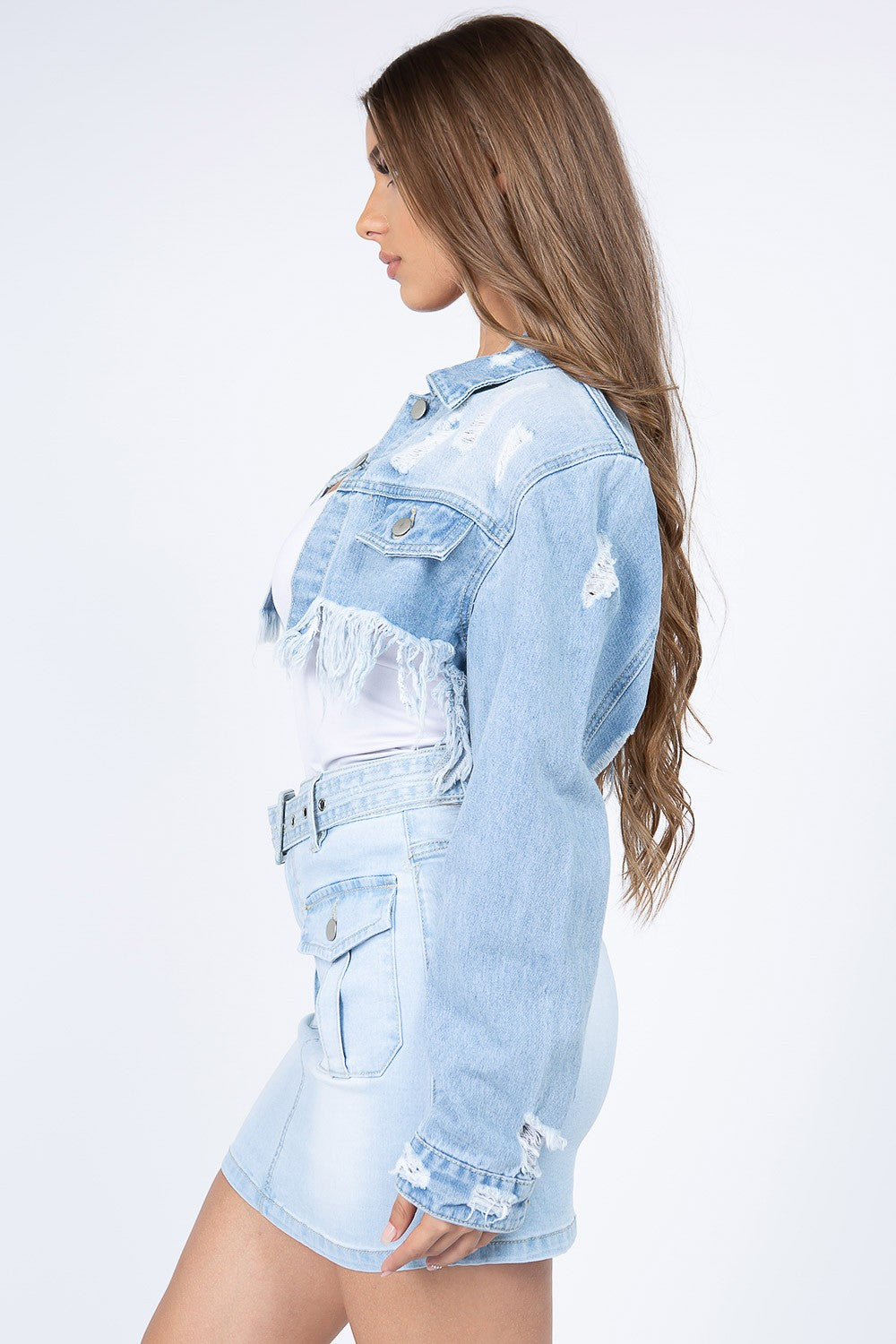 Woman wearing a distressed denim jacket with frayed hem, showcasing stylish raw edges and vintage button fly closure.