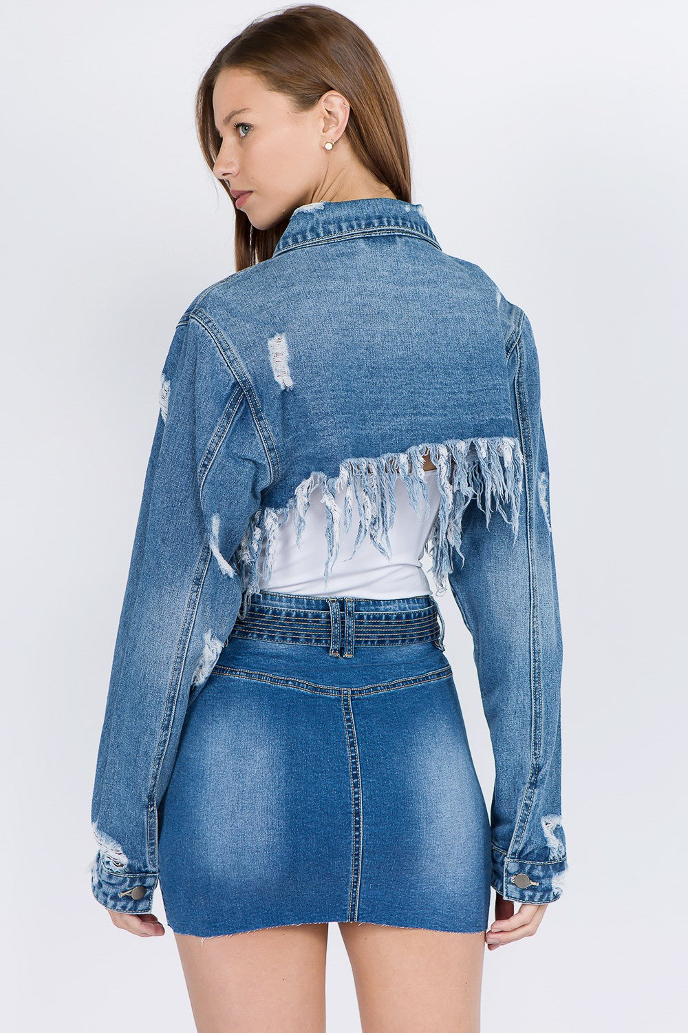 Woman modeling distressed denim jacket with frayed hem, showcasing edgy style and relaxed fit, perfect for versatile casual wear.