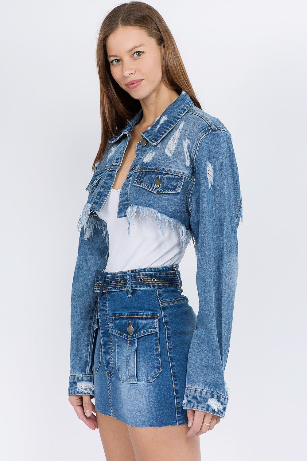 Model wearing distressed denim jacket with frayed hem and matching skirt, showcasing an edgy and stylish casual look.