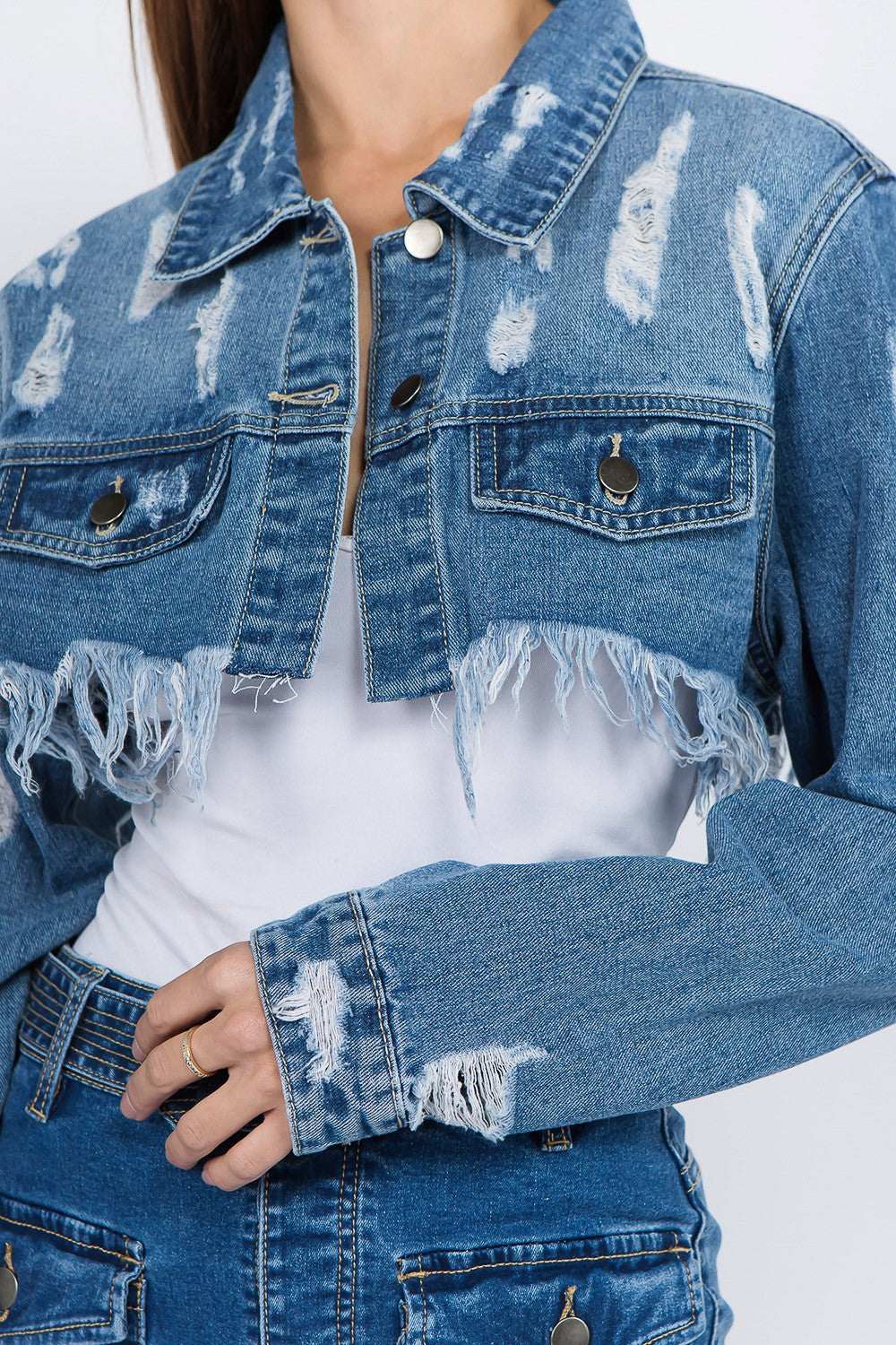 Distressed denim jacket with frayed hem, featuring a button-front closure, relaxed fit, and edgy raw details for trendy style.