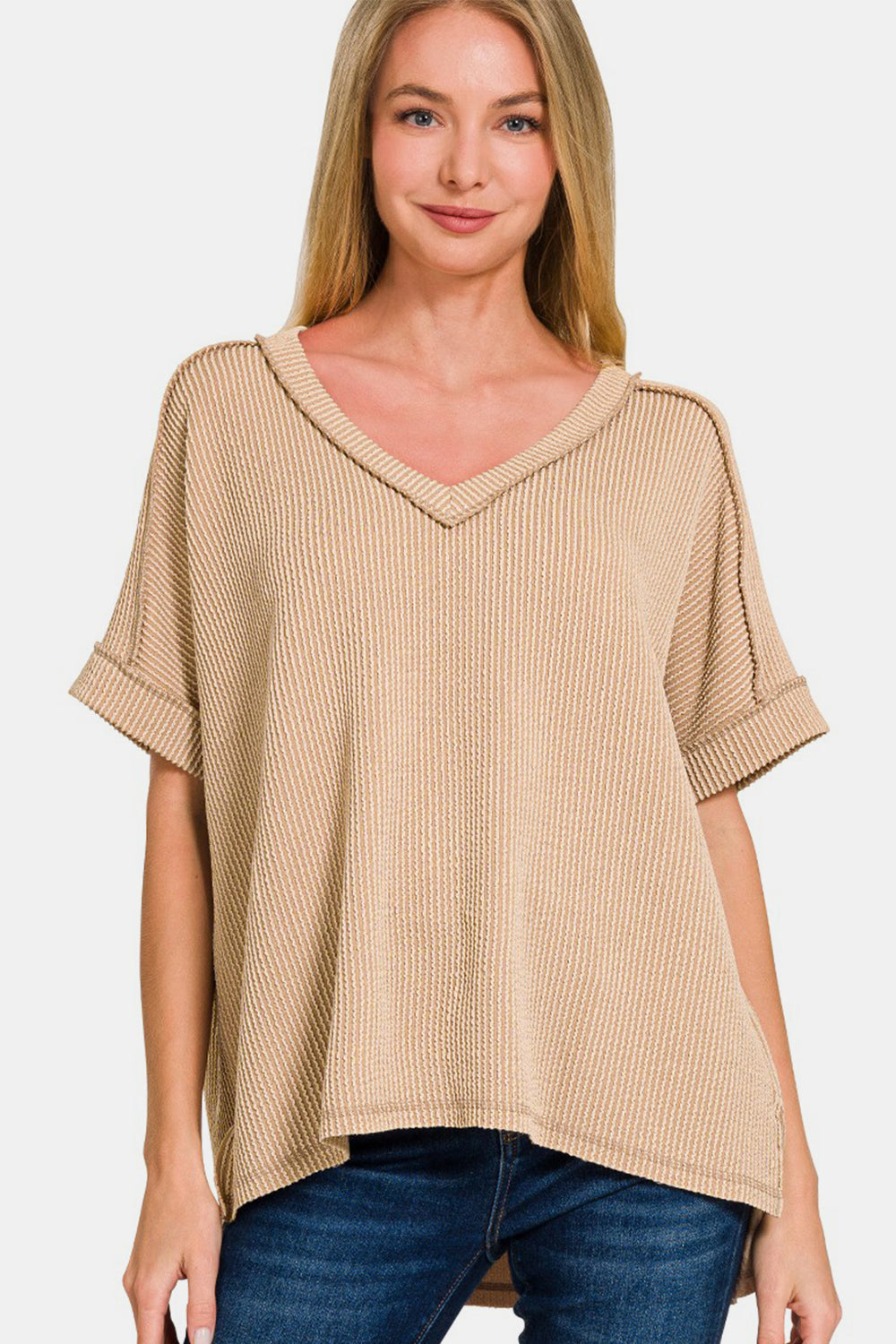 Woman wearing chic corded rib short sleeve high-low v-neck t-shirt with exposed seams and relaxed fit in beige.