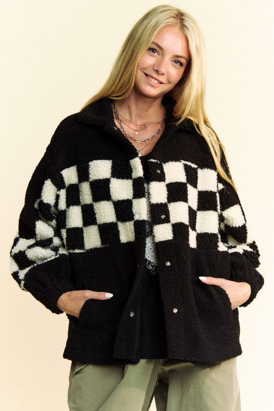 Woman wearing black full-size faux fur jacket with checkered pattern, featuring snap-down design and pockets.