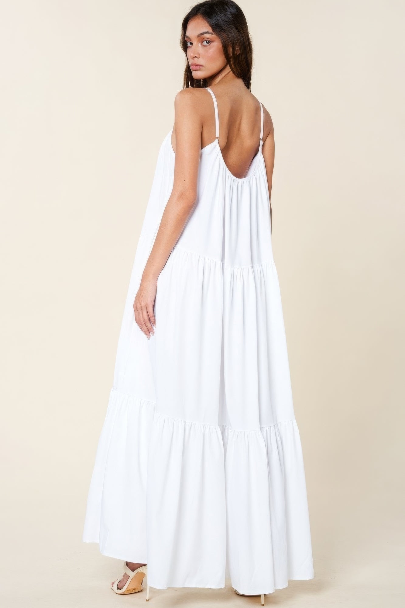 Woman wearing a white maxi sun dress with adjustable straps and side pockets, showcasing a flowy A-line cut in a lightweight fabric.