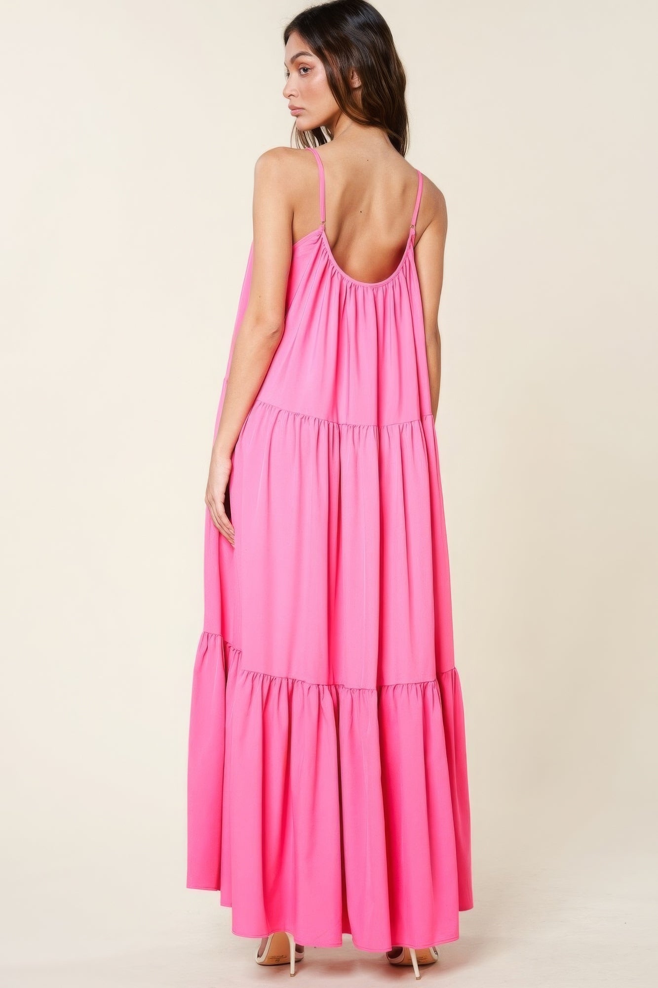 Woman wearing a pink maxi sun dress with adjustable straps and a flowy A-line cut, highlighting the back view and elegant design.