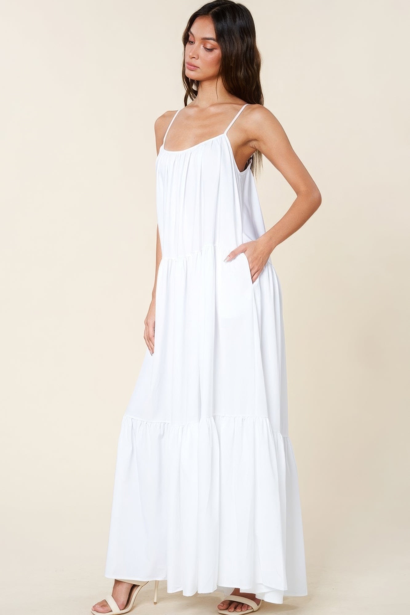 Woman wearing white maxi sun dress with pockets and adjustable straps, showcasing flowy A-line cut and comfortable summer style.