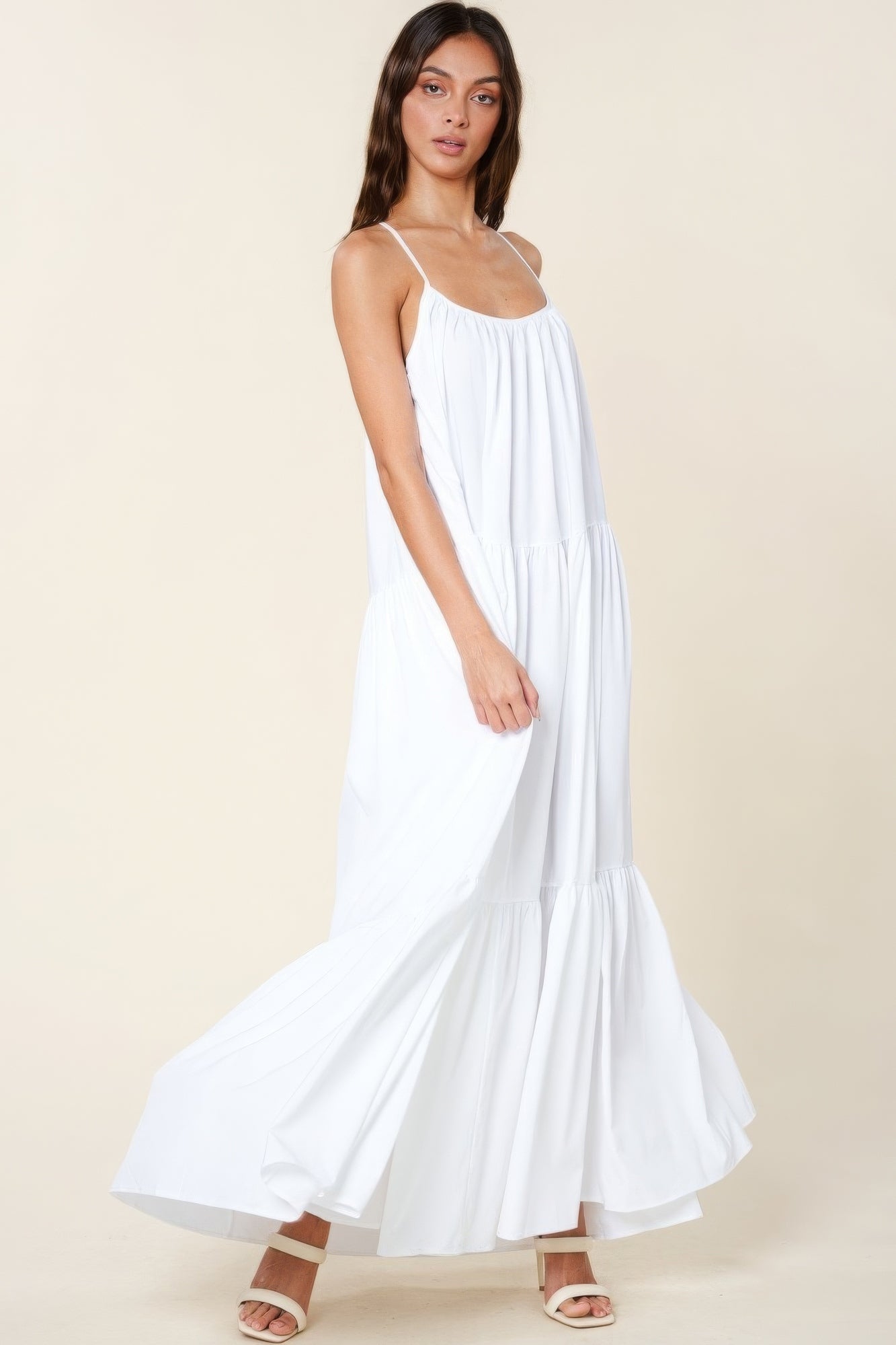 Woman wearing white maxi sun dress with adjustable straps and flowy A-line cut, perfect for summer events and casual outings.