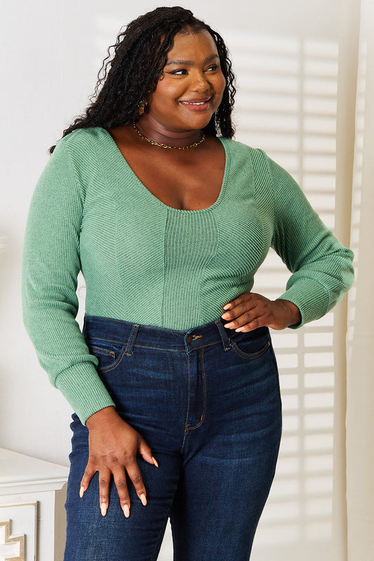 Woman wearing green scoop neck long sleeve top with jeans, showcasing a flattering and versatile wardrobe staple.