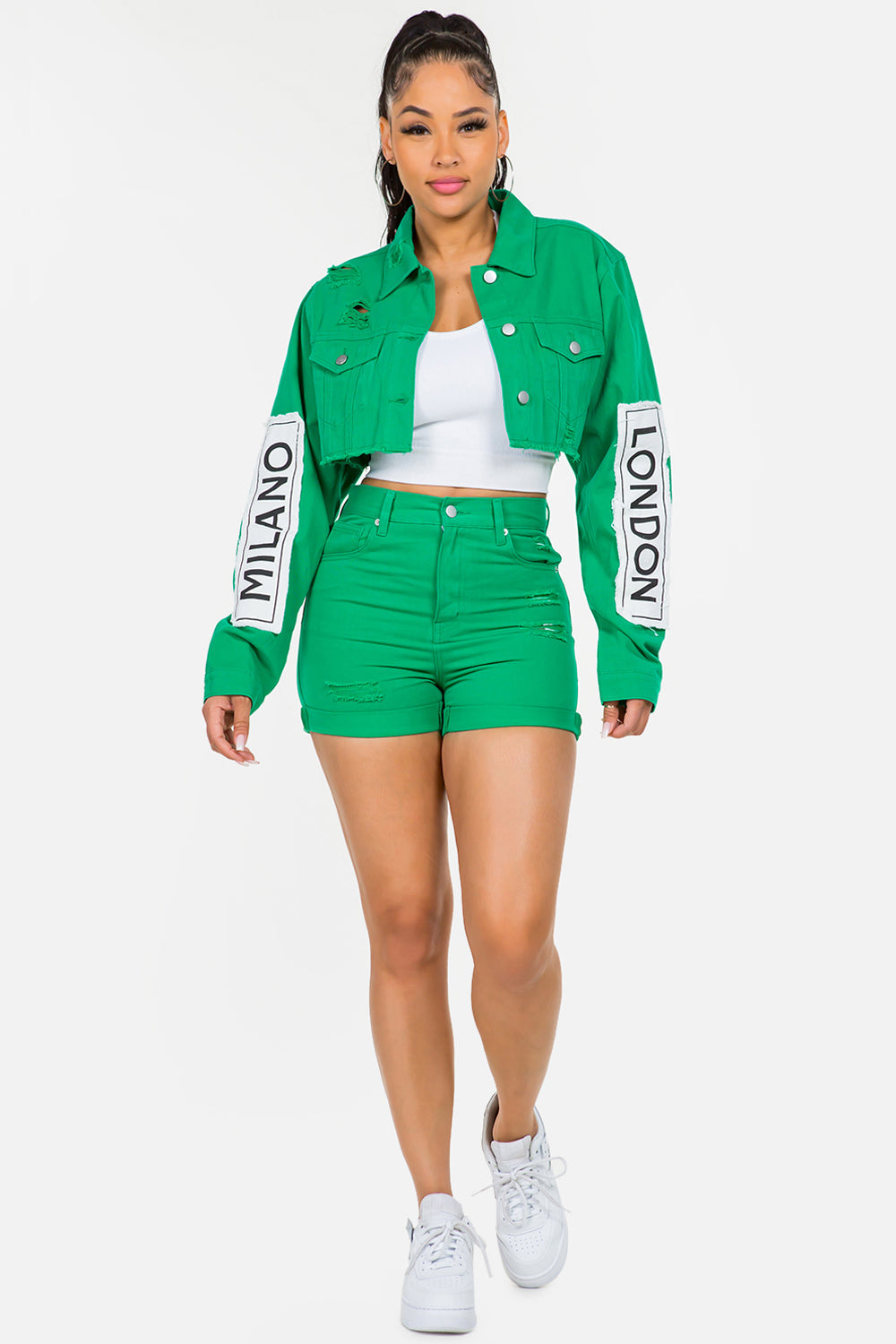 Woman wearing green high waist shorts and matching jacket with white sneakers, showcasing a trendy casual look.